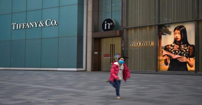 FILE PHOTO: Child wearing a face mask runs past stores of Tiffany & Co and Miu Miu, as the