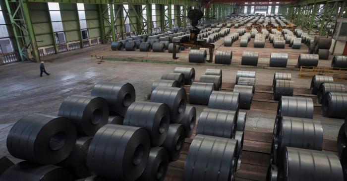 FILE PHOTO: Worker walks by steel rolls at the Chongqing Iron and Steel plant in Changshou
