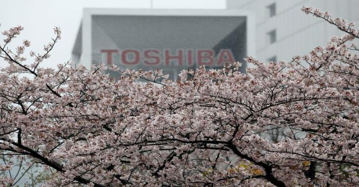 The logo of Toshiba Corp is seen behind cherry blossoms at the company's headquarters in Tokyo