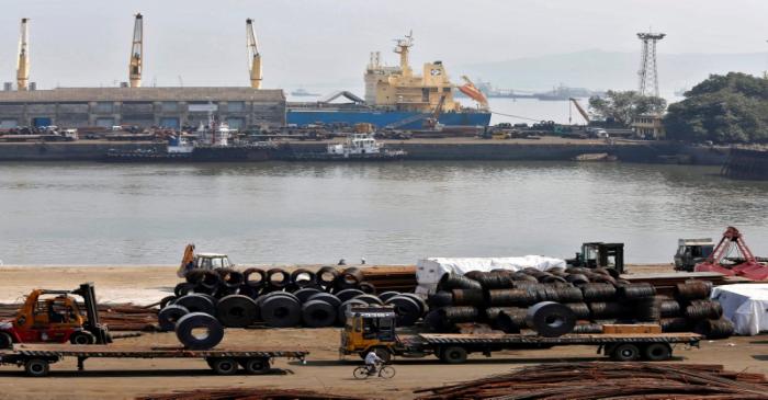 FILE PHOTO: A worker rides his bicycle past steel rims in a dockyard at Mumbai Port Trust in