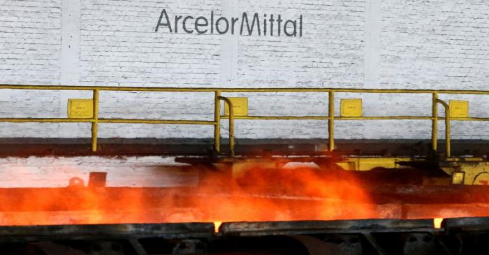 FILE PHOTO: The logo of ArcelorMittal is pictured in front of heat rising from a red-hot steel