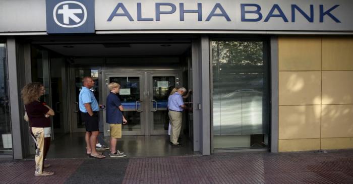 FILE PHOTO: People line up at an ATM outside an Alpha Bank branch in Athens