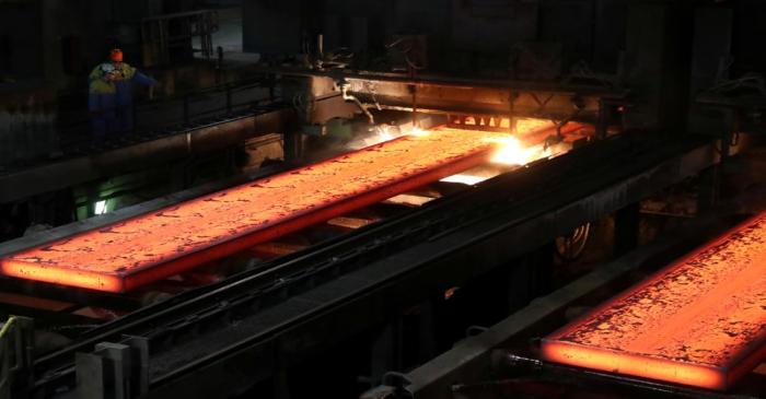 FILE PHOTO: Red-hot steel plates pass through a press at the Tata steel plant in Ijmuiden