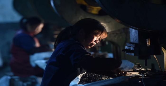 Employees work on a production line manufacturing metal parts for furniture at a factory in