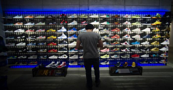 A man stands in front of a rack with Adidas Original shoes before the opening at the new Adidas