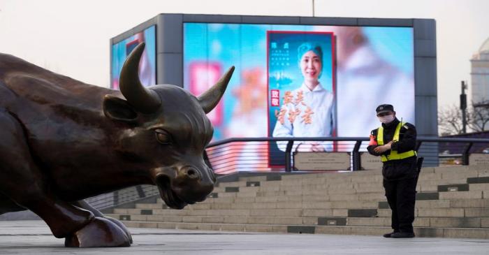 FILE PHOTO: Security guard wearing a face mask stands near the Bund Financial Bull statue and a