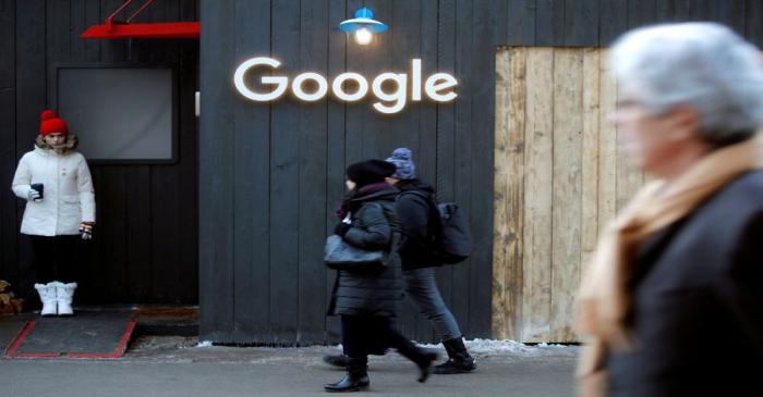 FILE PHOTO: People walk past the logo of Google in Davos
