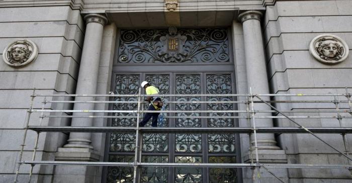 A construction worker stands on a scaffolding at the Bank of Spain in central Madrid, Spain