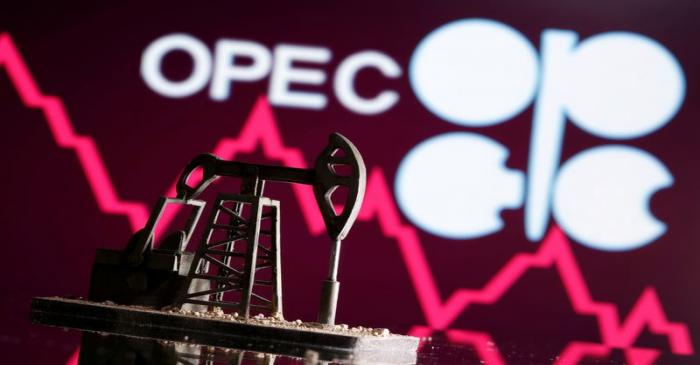 A 3D printed oil pump jack is seen in front of displayed stock graph and Opec logo in this