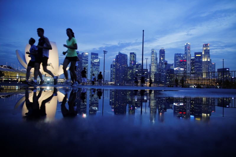 FILE PHOTO: Joggers run past as the skyline of Singapore's financial district is seen in the