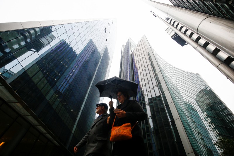 People walk through the financial district during rainy weather in London