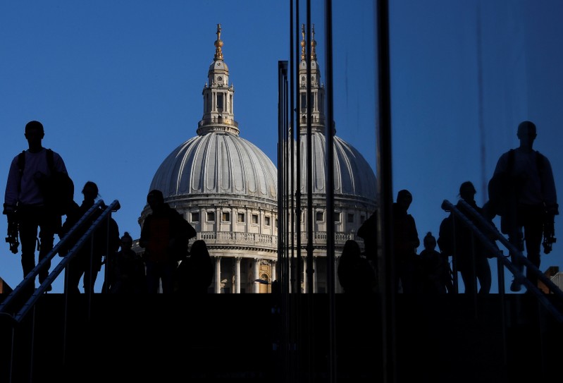 Workers are seen crossing the Millennium Bridge, with St Paul's Cathedral seen behind during