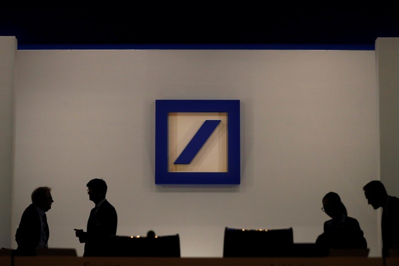 FILE PHOTO: People are silhouetted next to the Deutsche Bank's logo prior to the bank's annual