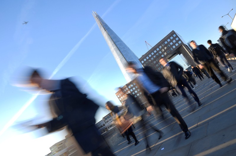 Workers are seen crossing London Bridge with The Shard seen behind during the morning rush hour