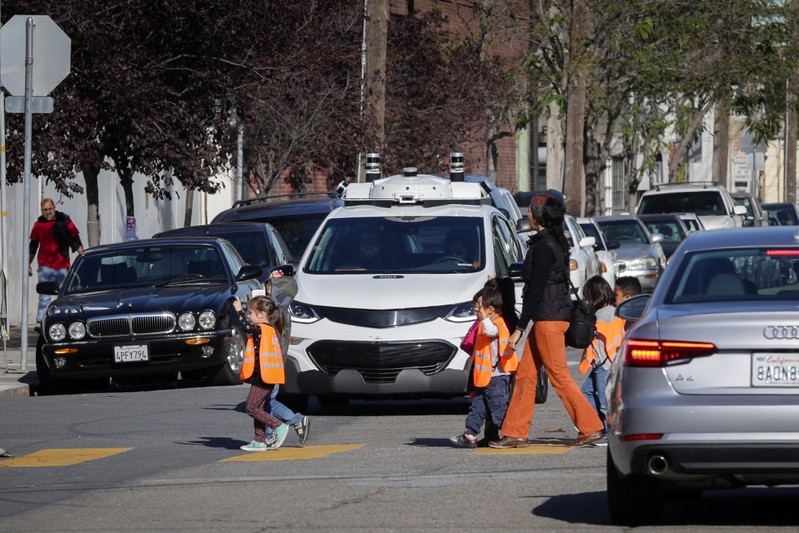 FILE PHOTO: Children pass by a self-driving GM Bolt EV during a media event in San Francisco