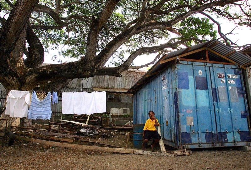 FILE PHOTO: A young boy sits next to a small shelter made from a disused shipping container in