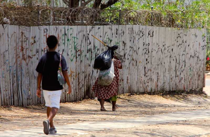 FILE PHOTO: Women walk past a barbed-wire fence along a street in Port Moresby