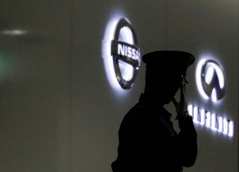 A security guard is seen in front of Nissan and Infiniti logos at Nissan Motor Co.'s global