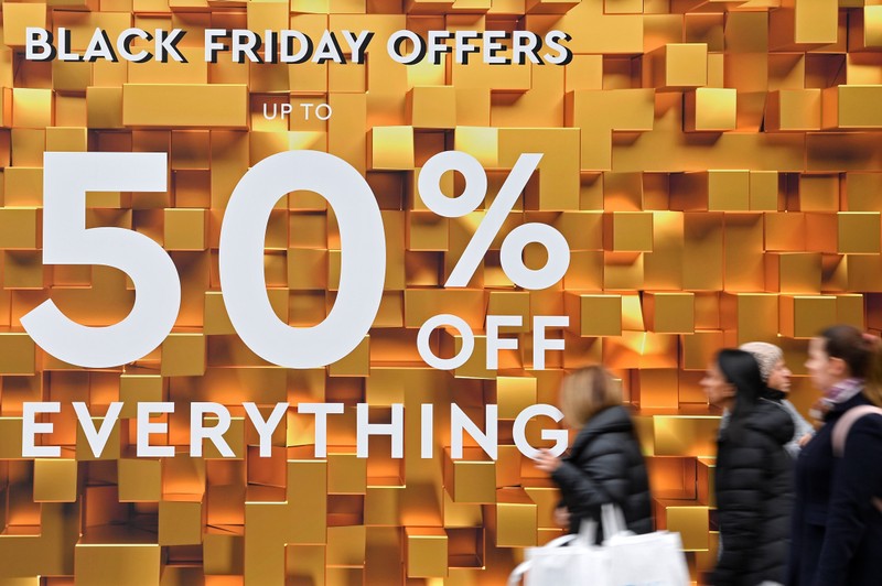 Shoppers walk past Black Friday signage on Oxford Street in London