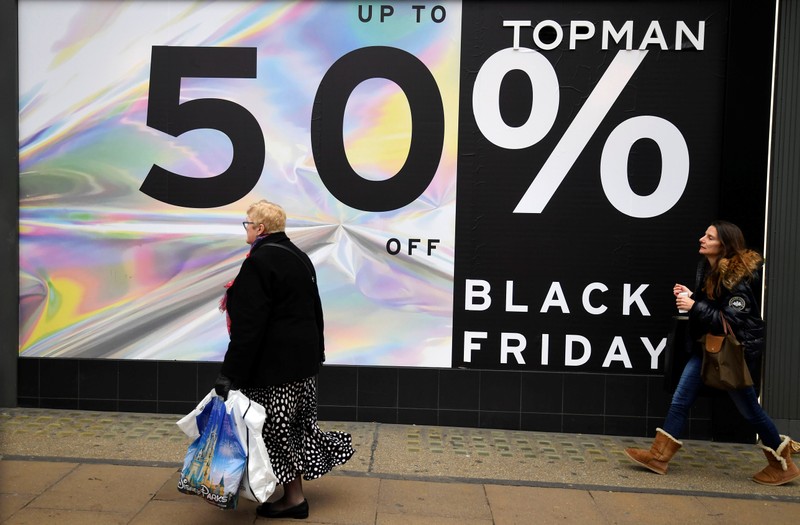Shoppers walk past Black Friday signage on Oxford Street in London