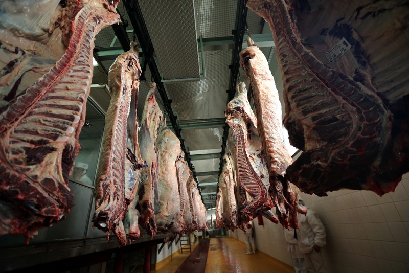 Workers walk behind beef carcasses at the Ecocarne Meat Plant slaughterhouse in San Fernando