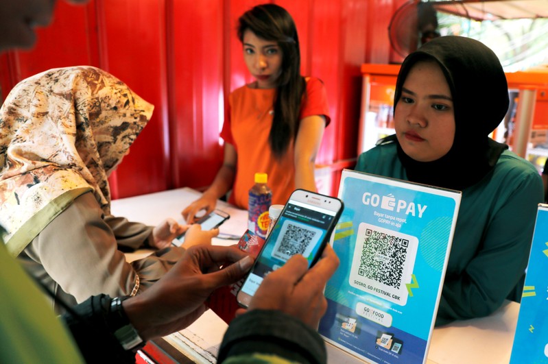 A customer uses a smartphone to scan code during pay food using Go Pay at a food counter during