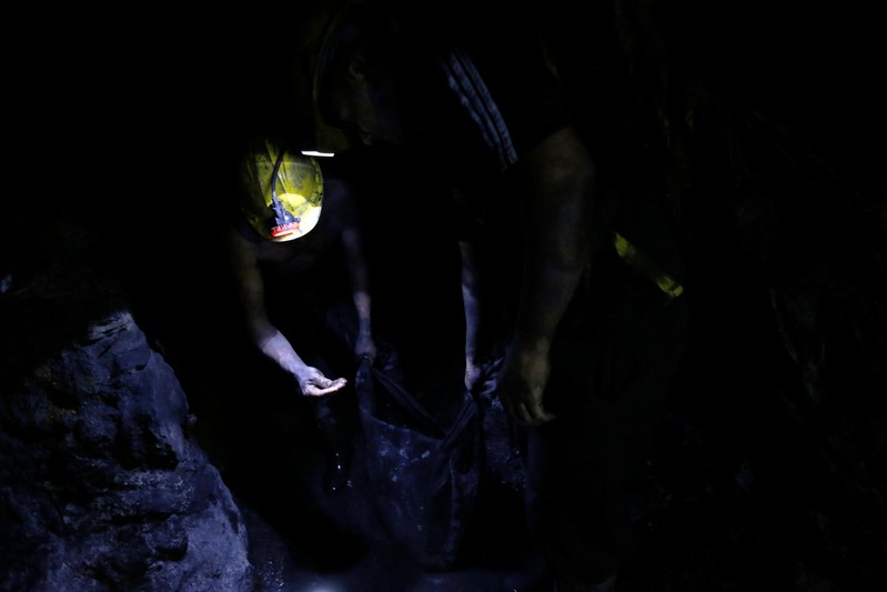 An informal miner observes an emerald inside a mine of the company Fura in Coscuez
