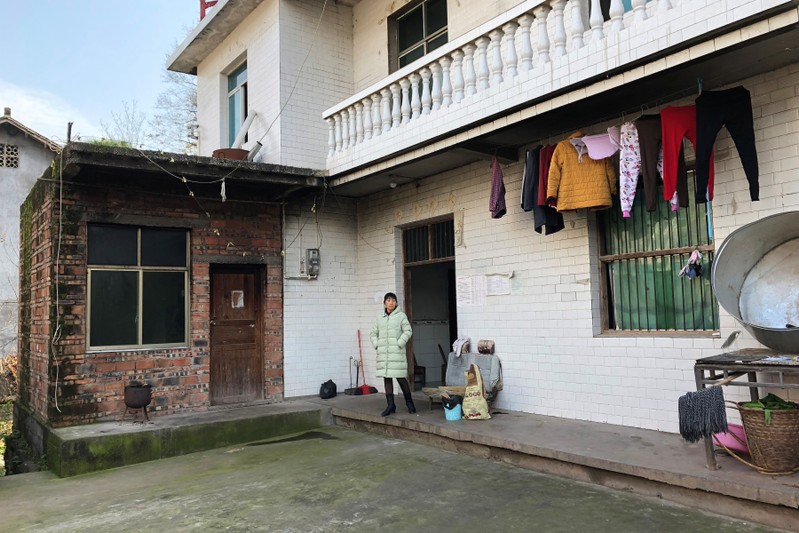 Wife of silicosis patient Wang Zhaohong stands in front of their house in Sangzhi