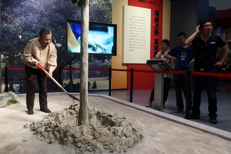 Visitors look at an exhibit showing the  former Chinese leader Deng Xiaoping planting a tree at