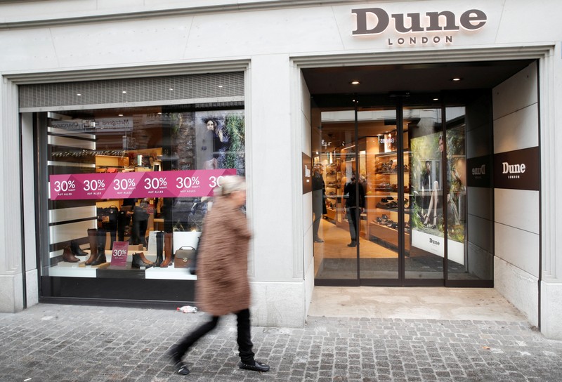 FILE PHOTO: A woman walks past a shop of British fashion footwear and accessories company Dune