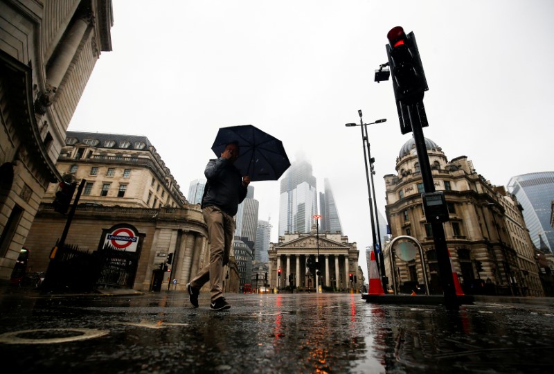 FILE PHOTO: People walk through the financial district during rainy weather in London
