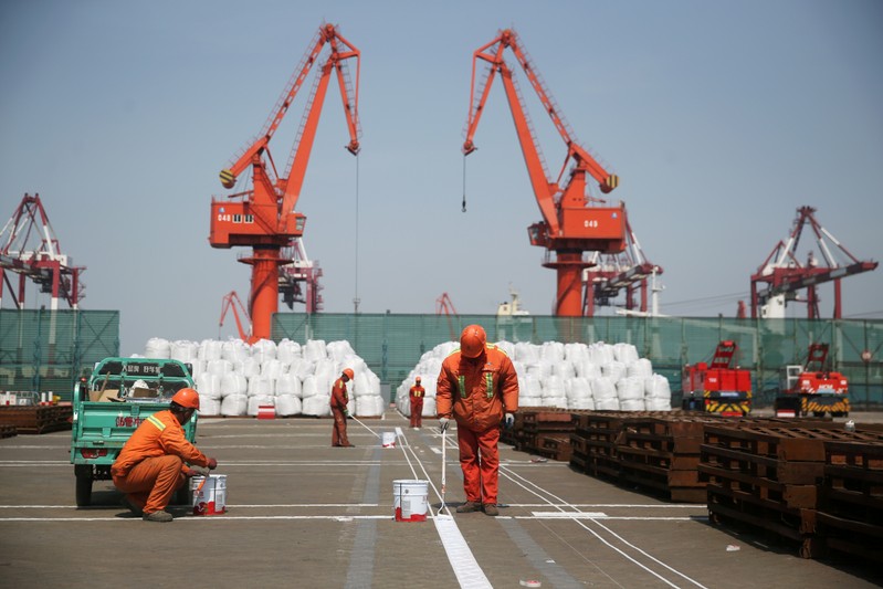 FILE PHOTO: Workers paint the ground at a port in Qingdao