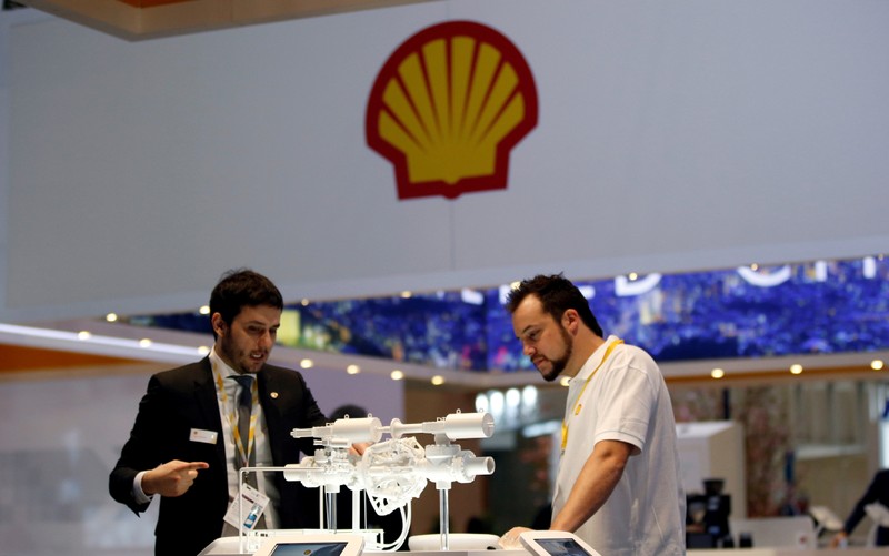 FILE PHOTO: Staff members work at the booth of Royal Dutch Shell at Gastech, the world's