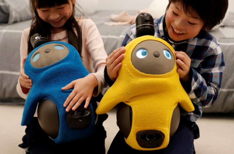 Children hold GROOVE X's new home robot LOVOT at its demonstration during the launching event