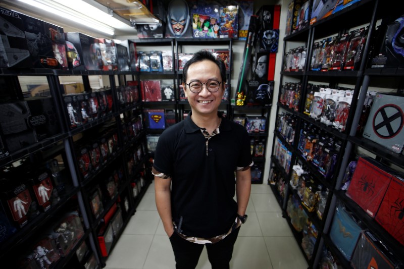 Andy Kurniawan, who is the owner of an action figure store, poses for a photograph at his store