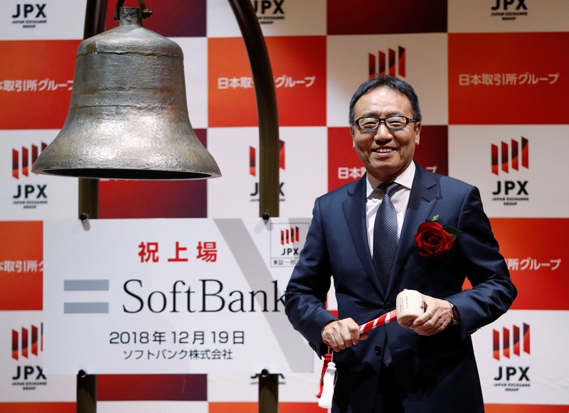 SoftBank Corp. President and CEO Ken Miyauchi smiles as he rings a bell during a ceremony to