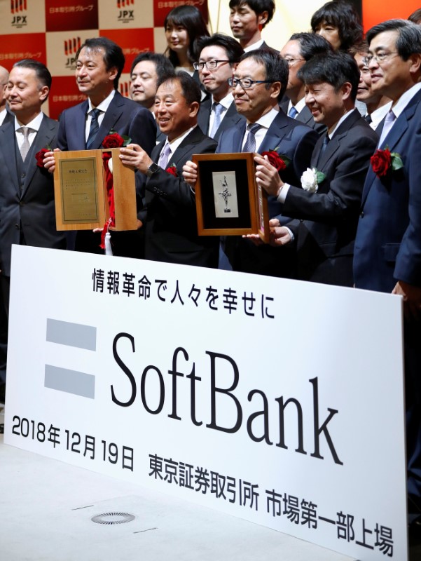 SoftBank Corp. President and CEO Ken Miyauchi poses as he holds an IPO certificate with Tokyo