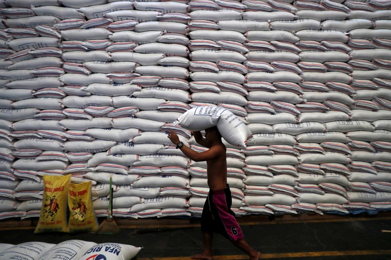 FILE PHOTO: A worker carries on his head a sack of rice inside a government rice warehouse
