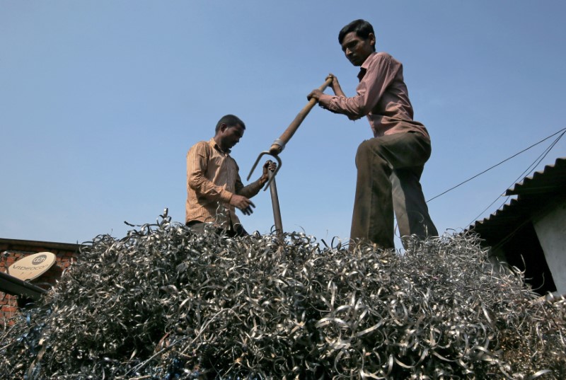 FILE PHOTO: Workers flatten metal scrap on a supply truck at an industrial area in Mumbai