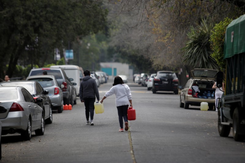 People carry plastic containers with fuel close to a gas station Mexico City