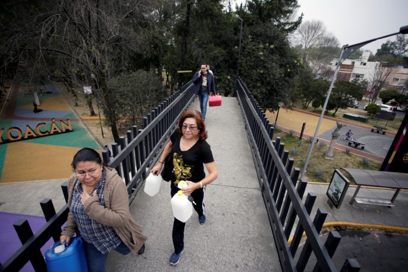 People carry empty plastic containers to buy gasoline at a gas station in Mexico City