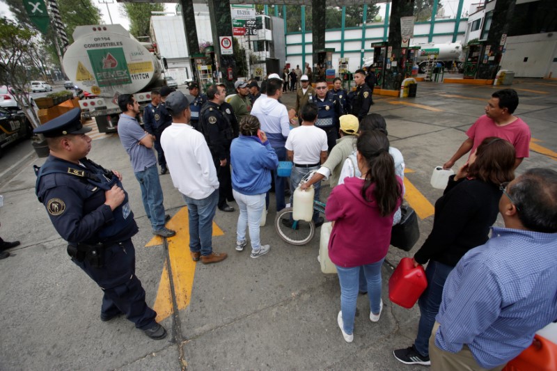 People queue to buy gasoline outside at a gas station in Mexico City
