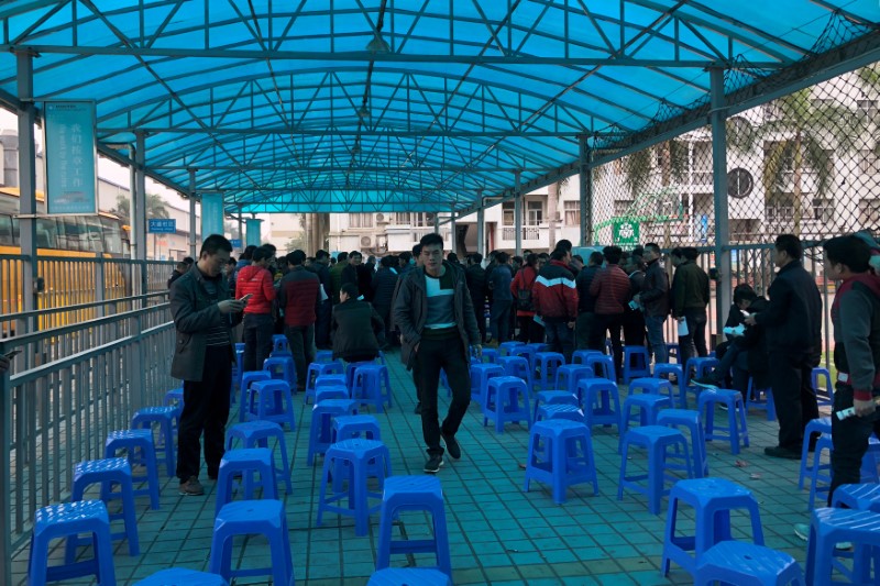 Men are seen at a booth set up by local authority to educate workers on Chinese labour law,