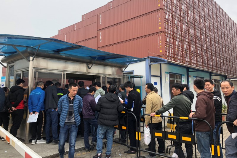 Workers queue to collect their employee contract termination letters at a Maersk container