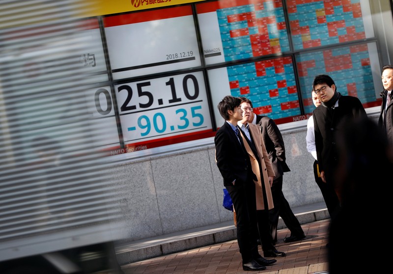 Men stand in front of a stock quotation board outside a brokerage in Tokyo