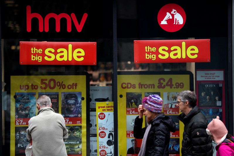 Pedestrians walk past an HMV shop in central London