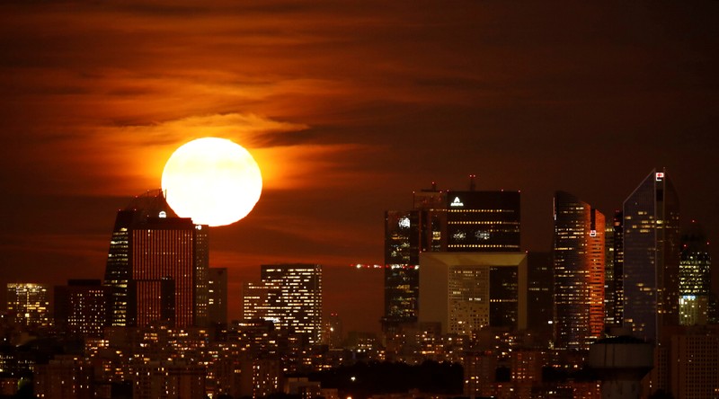 FILE PHOTO: The moon rises over the financial district of La Defense just after sunset near