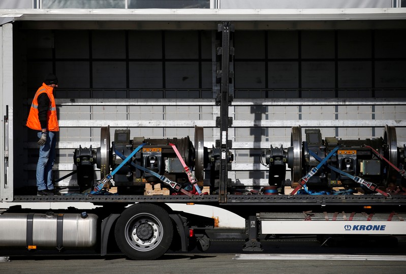 A worker prepares elements of bogies for transport on a lorry, at the Alstom high-speed train