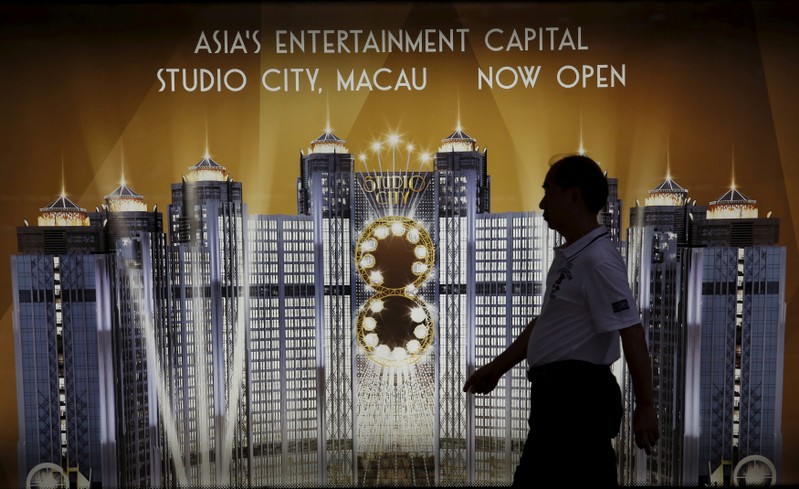 FILE PHOTO: A man walks past an advertisement of Macau's Studio City resort, owned by Melco