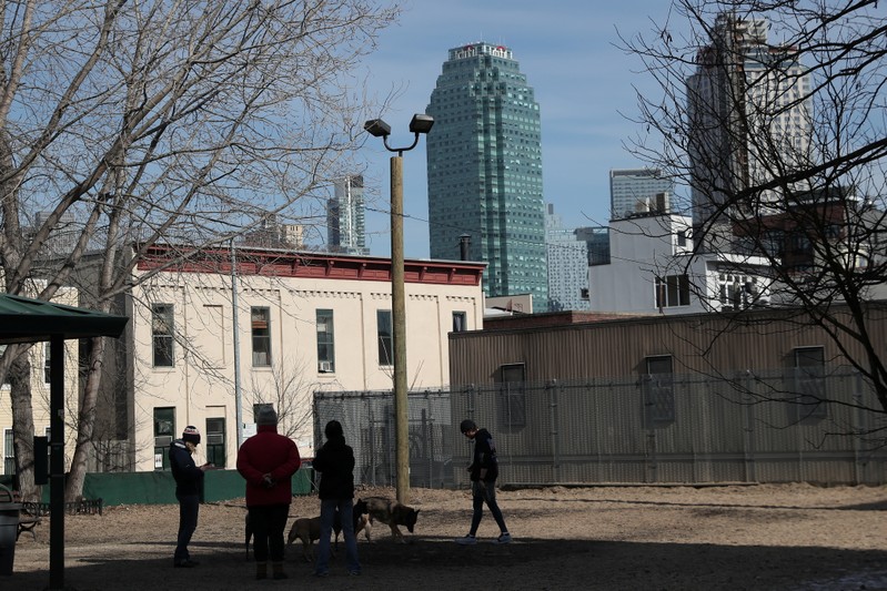 People stand in a dog walking park in the Long Island City section of the Queens borough of New